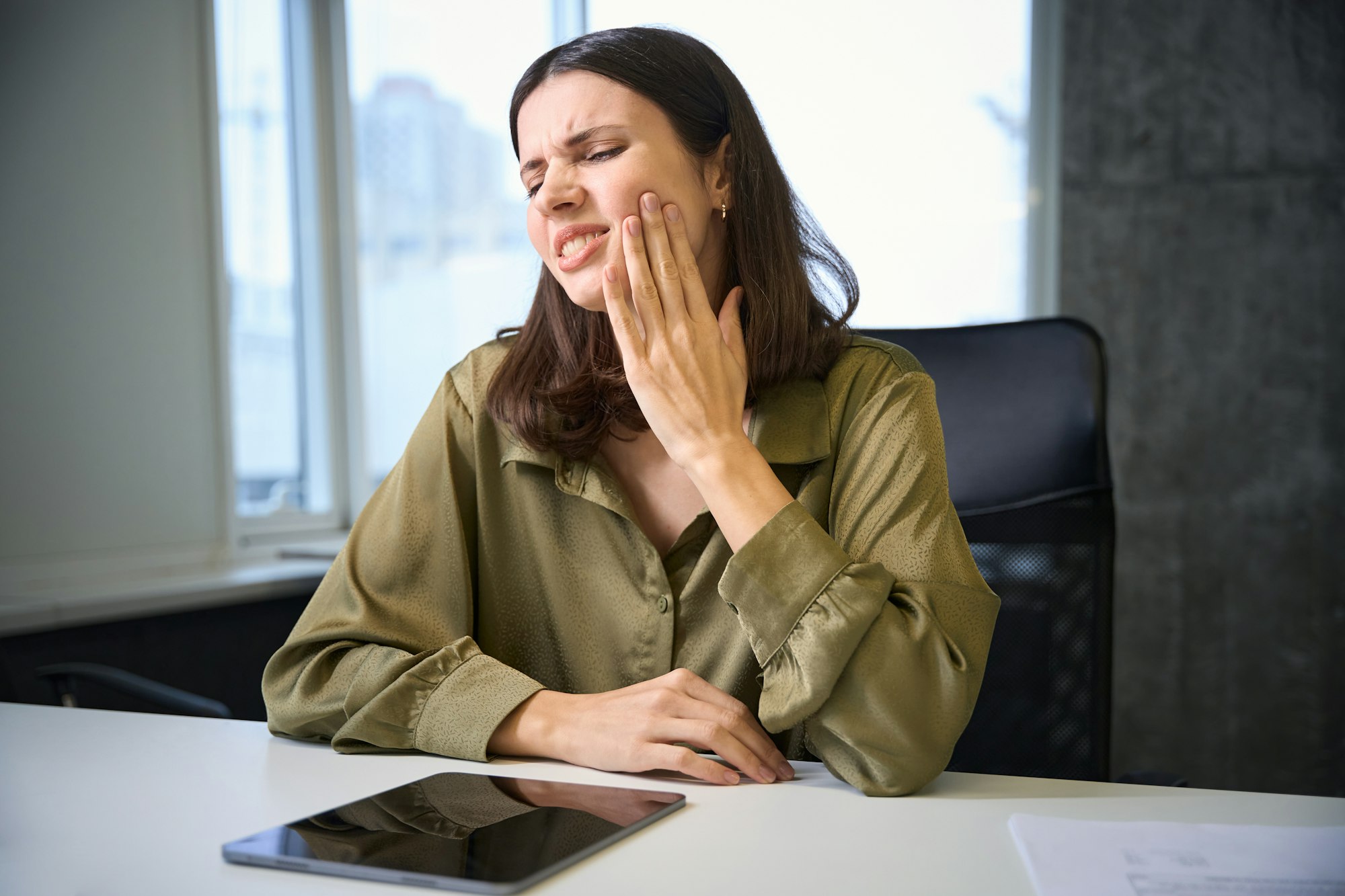 Business woman feeling toothache while working with tablet